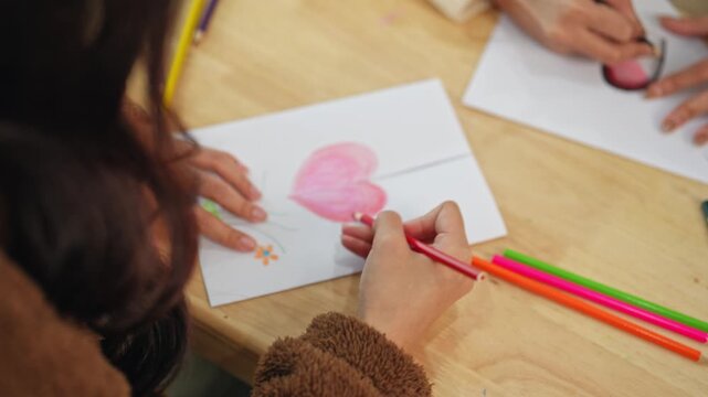 Young person engaging in creative drawing activity with colorful crayons on a wooden table, showcasing artistic expression and childhood creativity