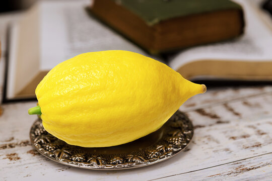 Jewish festival of Sukkot traditional symbols yellow etrog is placed on silver dish next to an open book
