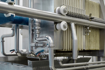 Steel pipelines, tubes and tanks at brewery. Close up of beer production filters