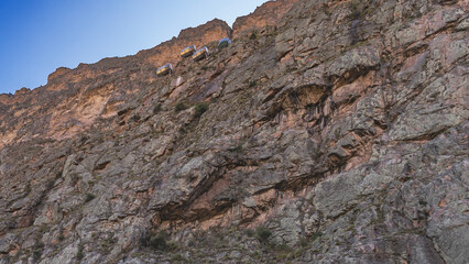 A unique capsule hotel on the mountainside. Sky lodge. Three residential lodges and a restaurant are attached to a sheer cliff at a high altitude. Bottom-up view. The blue sky. Peru. Cusco.  Urubamba 