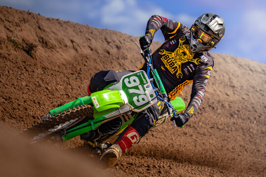 Latvia, Kandava, 2025-08-23, Latvijas kauss A motocross racer in full gear takes a sharp turn on a dusty track