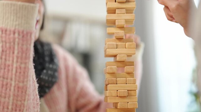 Focused individual stacking wooden blocks in a calm indoor environment showcasing concentration and creativity during a leisure activity or game