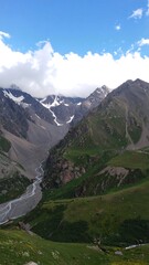 Obraz premium High-angle view of a valley with a river snaking through it, mountains rising on either side, and patches of snow visible on the higher peaks