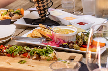 Appetizers of Hummus Platter, French Fries with Dip and Flatbread Pizza on a crowded table top at a restaurant