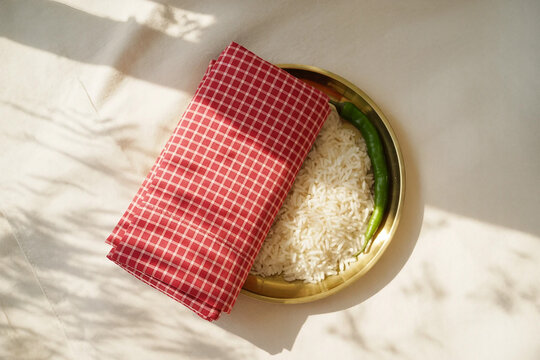 Flatlay of Traditional Gamcha with Brass Plate, Rice and Green Chili