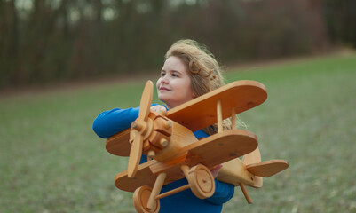 Kids dream. Happy kid play with wooden plane outdoor. Child playing with toy airplane. The dream of...