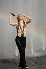 Young woman splashing in a city fountain. Wet girl in fountain on hot summer day. Playful funny...