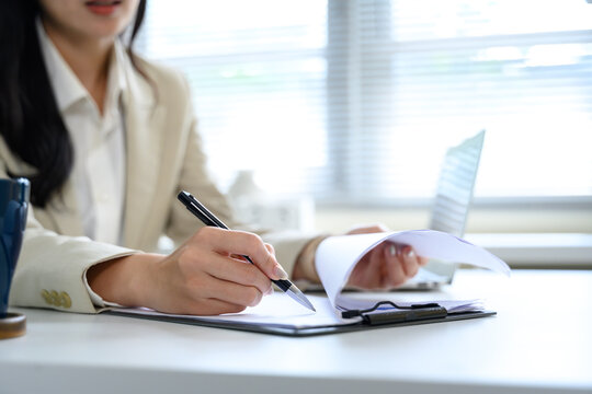 Close up of businesswoman hands writing notes on a clipboard during office work