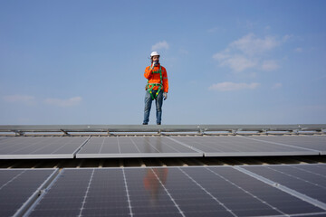 Blue collar worker is inspecting solar panel at rooftop of factory.