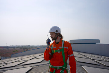 Blue collar worker is inspecting solar panel at rooftop of factory.
