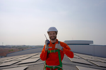 Blue collar worker is inspecting solar panel at rooftop of factory.
