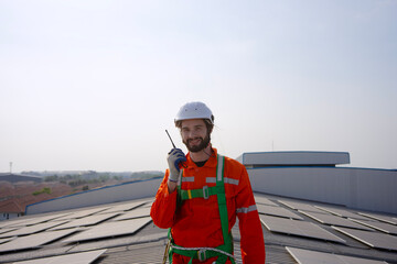 Blue collar worker is inspecting solar panel at rooftop of factory.