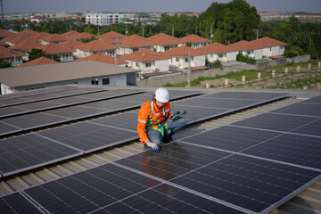 Blue collar worker is inspecting solar panel at rooftop of factory.