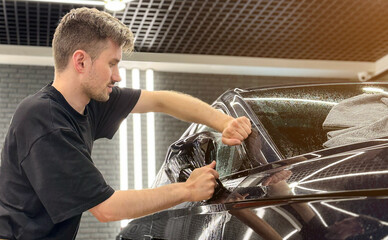 A car wrapping specialist applies a polyurethane film to the car. Detailer smoothes PPF. Car...