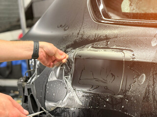 A car wrapping specialist applies a polyurethane film to the car. Detailer smoothes PPF. Car...