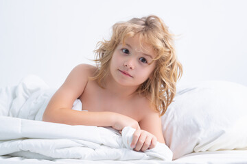 Fototapeta premium Little child under blanket in bed, just wake up.