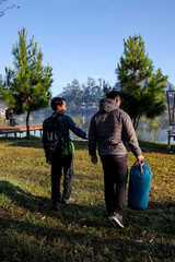 Two Men Walking And Carrying Backpack And The Other Sleeping Bag Near Lake