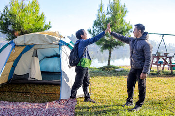 Two Happy Asian Men Giving Each Other High Five After Setting Up Tent By Scenic Lake