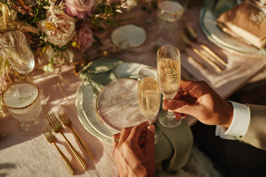 Elegant wedding table setting with champagne glasses, gold cutlery, floral centerpiece, and soft sunlight creates romantic celebration atmosphere for special event or upscale gathering