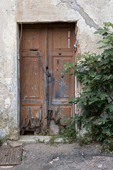 old, rotten wooden door with partially rotten boards and steel chain