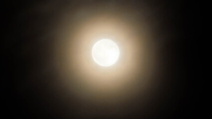Obraz premium Full moon glowing in the dark night sky with soft halo light around it. Beautiful astronomy, lunar, and night photography background.