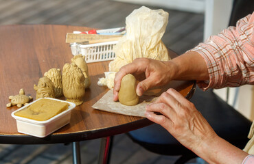 Person is making a clay sculpture on a table