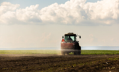 Fototapeta premium Tractor spreading artificial fertilizers in field