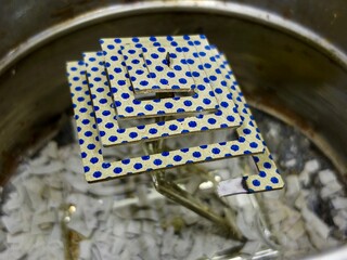 macro close-up of a unique mosquito coil with a blue polka-dot pattern on a golden surface, showing...