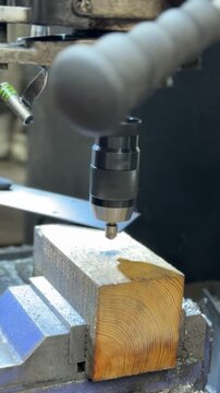 Industrial drill press machine countersinking holes on metal plates. Precision machining process in a factory environment. Concept of metalwork and production.