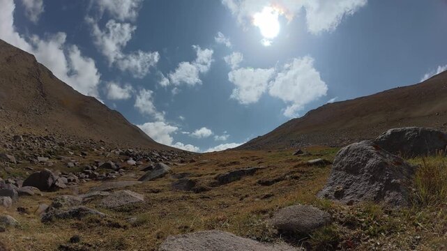 A timelapse of a cloudy sky with the sun at an altitude of 2734 meters above sea level, in the mountains of the Sairam-Ugam National Park in the Republic of Kazakhstan, Shymkent, Kaska-Su gorge.