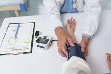 Doctor checking blood pressure of patient in clinic using automatic sphygmomanometer, healthcare...