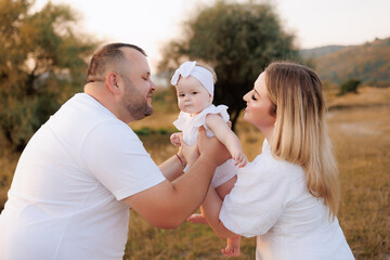 Fototapeta premium Cherishing family moments in a golden sunset meadow with joyful parents and their baby