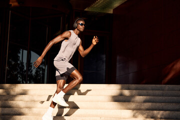 Focused man running on stairs while listening to music outdoors