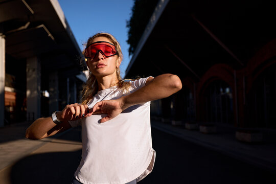 Female athlete adjusting her smartwatch during evening outdoor training