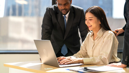 Diverse group of business professionals in formal collaborating during a corporate meeting, focused on technology and teamwork, asian businesswoman leading with laptop, teamwork and collaboration
