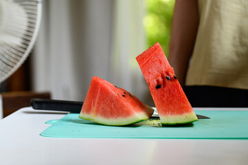 室内のテーブルに置かれた切ったスイカと回る首振り扇風機