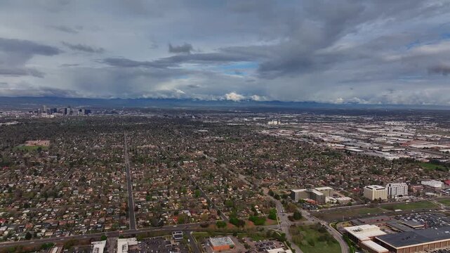 Front Range Denver Lowry Northfield Central Park Colorado aerial drone neighborhood apartment buildings sunny cloudy sky cloudy North High School cars cityscape skyscrapers forward pan up motion