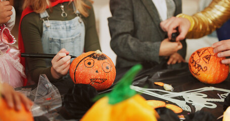 Hands, halloween and group with pumpkin, decoration and creativity with drawing, costume and party....