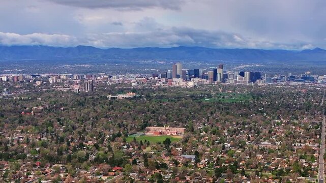 Front Range Denver Lowry Northfield Central Park Colorado aerial drone neighborhood apartment buildings sunny cloudy sky cloudy North High School cars cityscape skyscrapers forward pan up motion