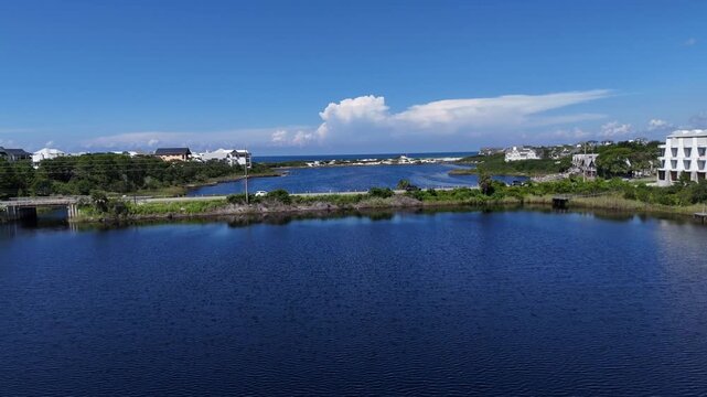 Aerial fly crossing the County Rd 30A highway at blue coastal Camp Creek Lake towards the ocean, 30A, Florida, USA