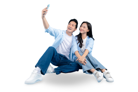 A cheerful couple taking a selfie and looking delighted. The two people are sitting together, both wearing casual clothes, and smiling warmly on PNG background - Powered by Adobe