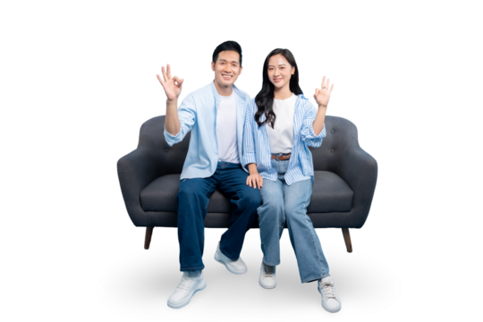 A couple happily sitting on the sofa while making the okay hand gesture on PNG background. This image is perfectly suited for a variety of uses, embodying themes of agreement and positivity. - Powered by Adobe