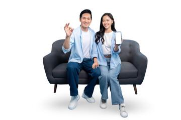 Happy couple smiling and showing mobile phone, ok gesture and sitting on couch. Couple with a phone...