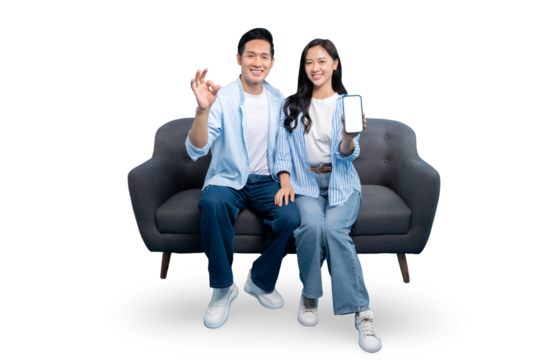 Happy couple smiling and showing mobile phone, ok gesture and sitting on couch. Couple with a phone smiling on PNG background