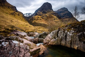 River Coe flows through Glen Coe with The Three Sisters mountains in early spring, Scotland