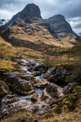 River Coe flows through Glen Coe with The Three Sisters mountains in early spring, Scotland