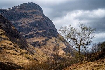 River Coe flows through Glen Coe with The Three Sisters mountains in early spring, Scotland