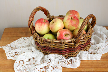 Wicker basket brimming with freshly picked apples on rustic wooden table