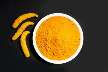 Indian spice called Turmeric powder with roots isolated on black background 