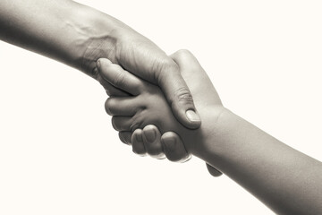 Dramatic photography of two hands of mother and child on a light background. Black and white.